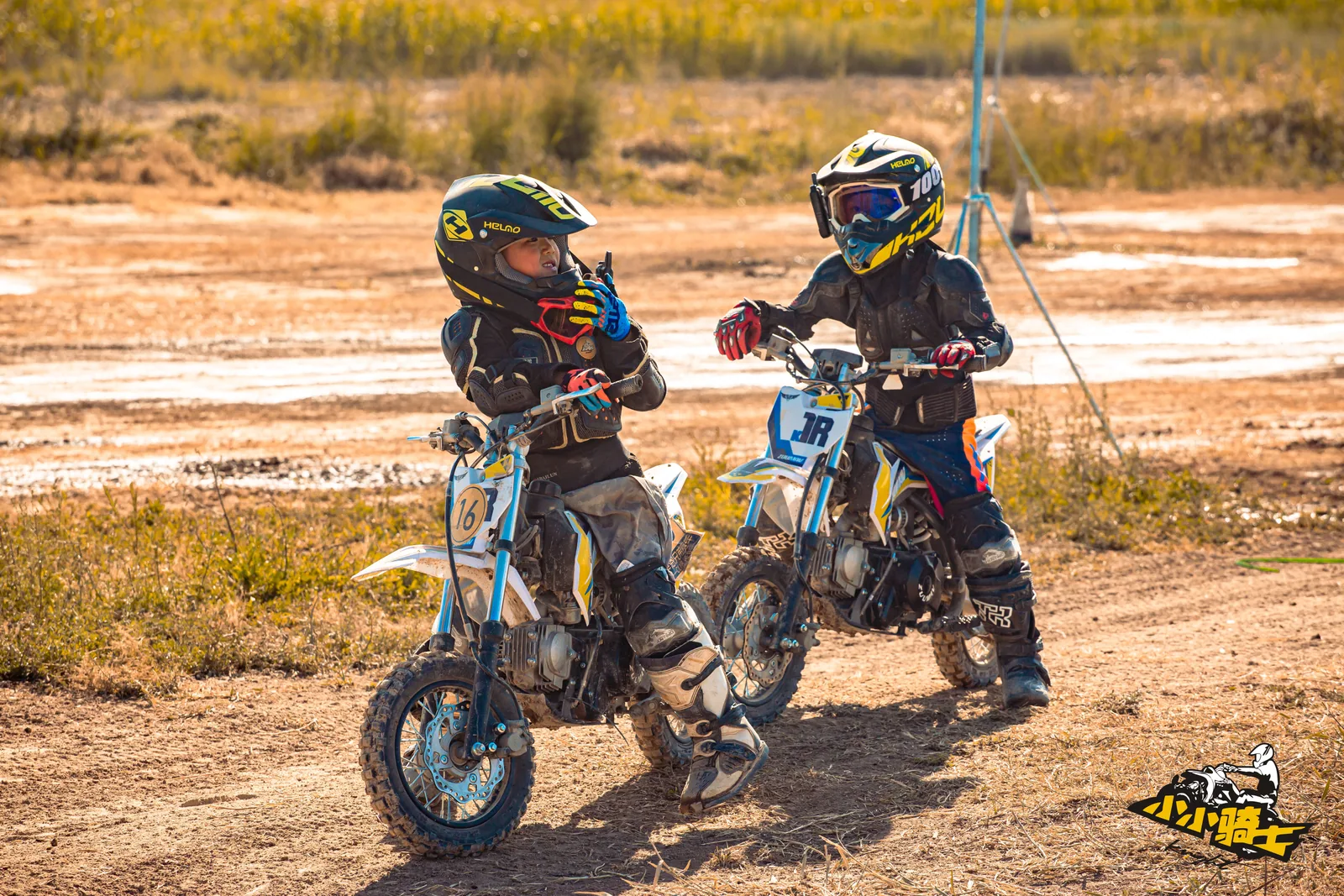 Two young riders pause beside the training route to communicate and check in
